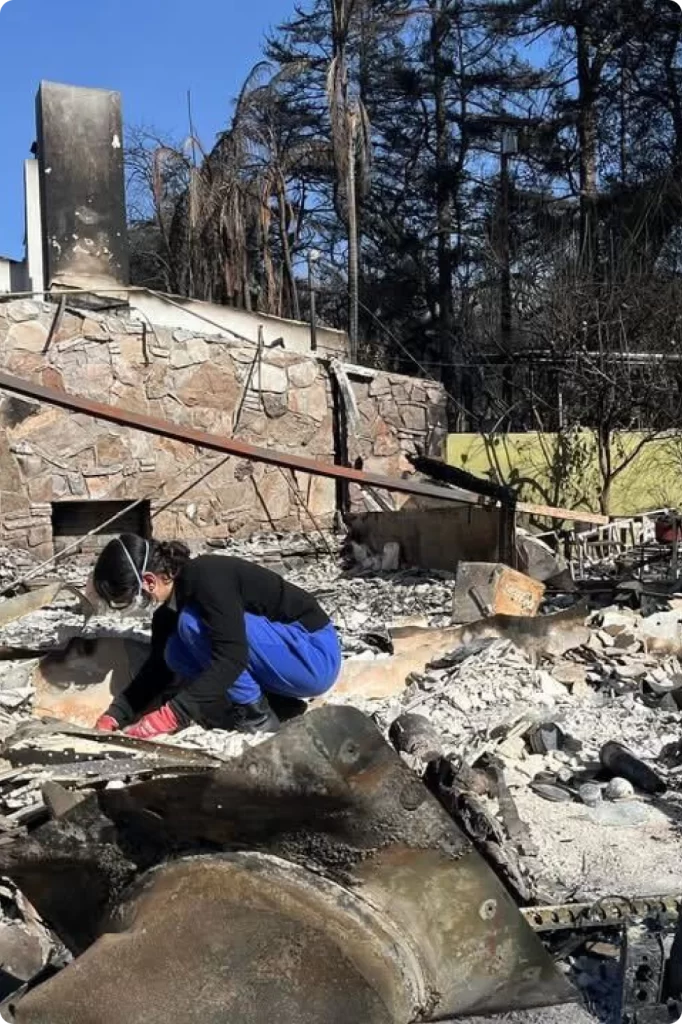 Photo of a relief worker sorting through the wreckage of a burnt home